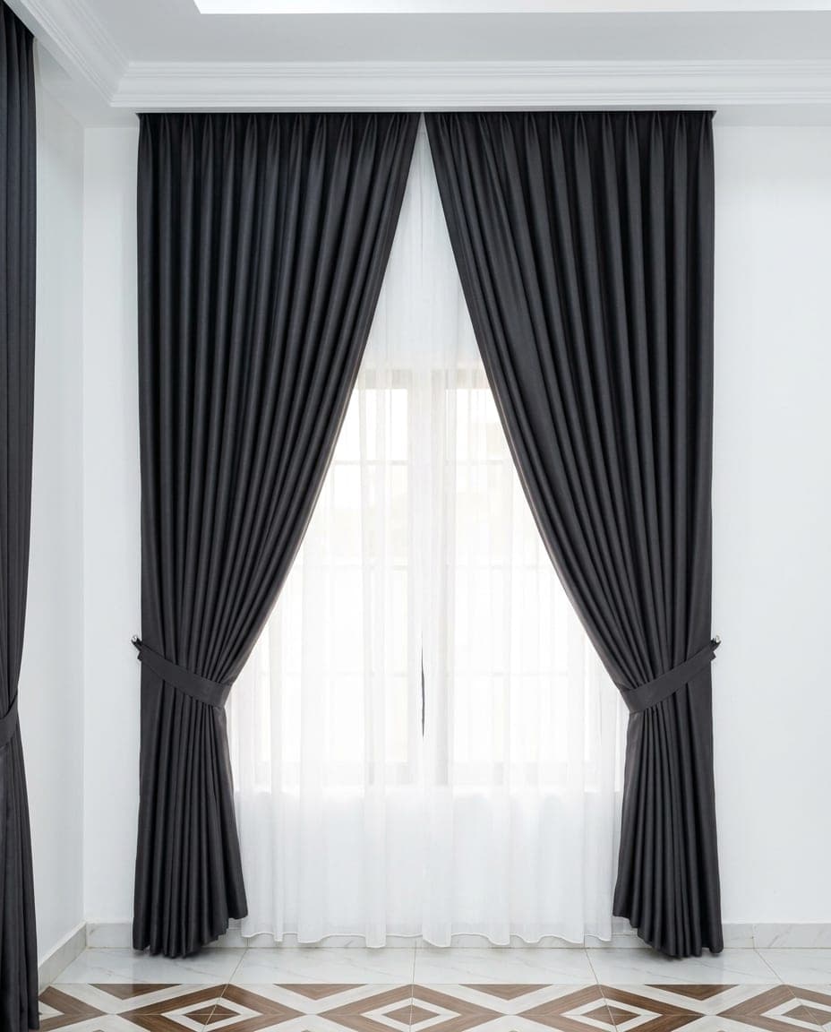 Charcoal curtains held back with tiebacks over a white sheer