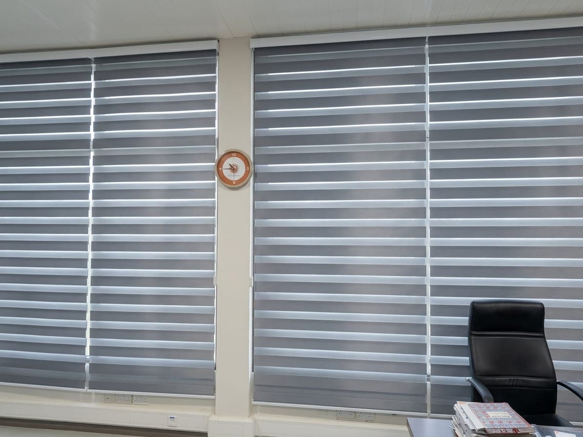 Grey zebra roller blinds across two large office windows